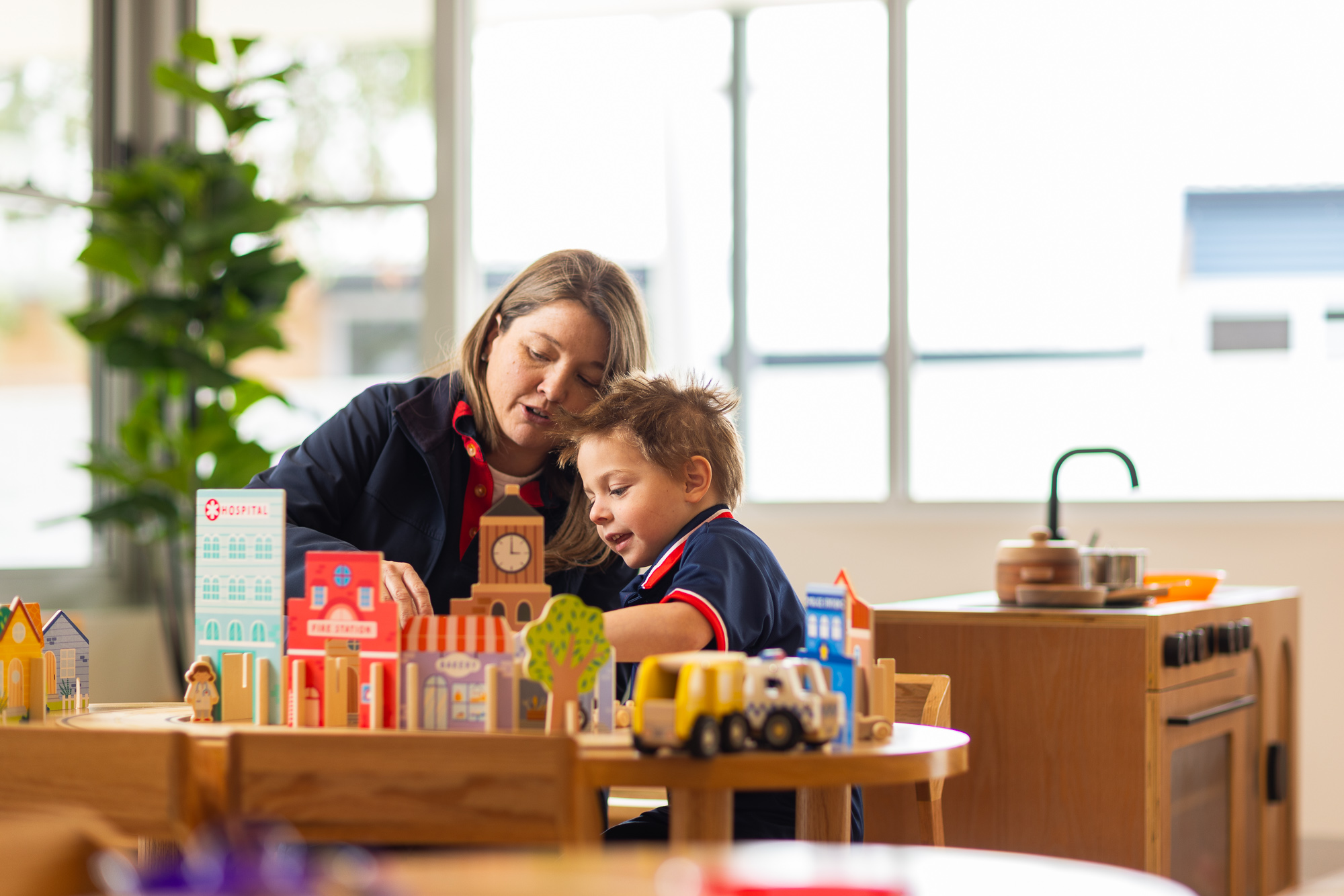 **Alt text:** Educator helping a child explore a miniature city during play-based learning at St Michael’s Early Learning Centre.