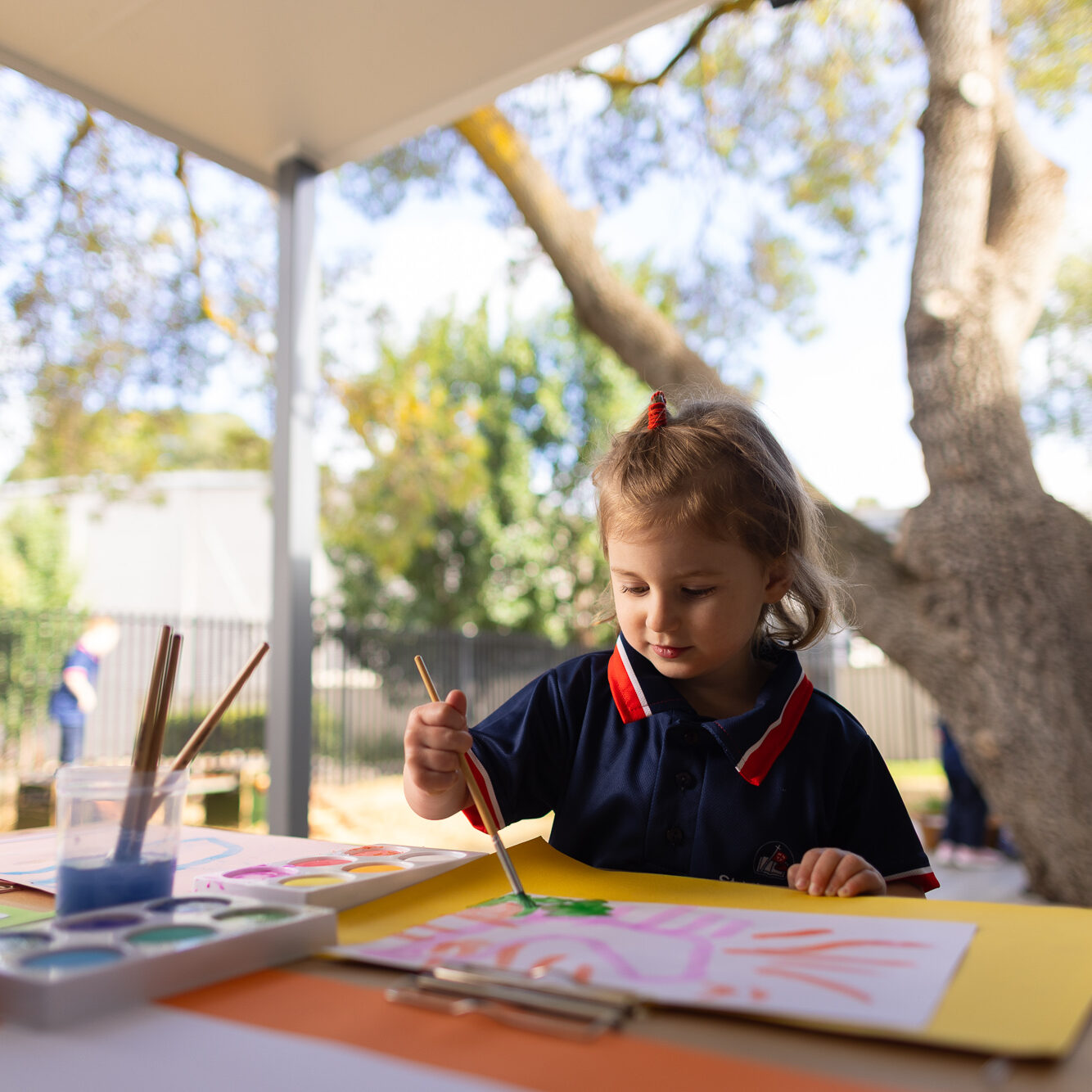 Child painting outdoors at an art activity table at St Michael’s Early Learning Centre.