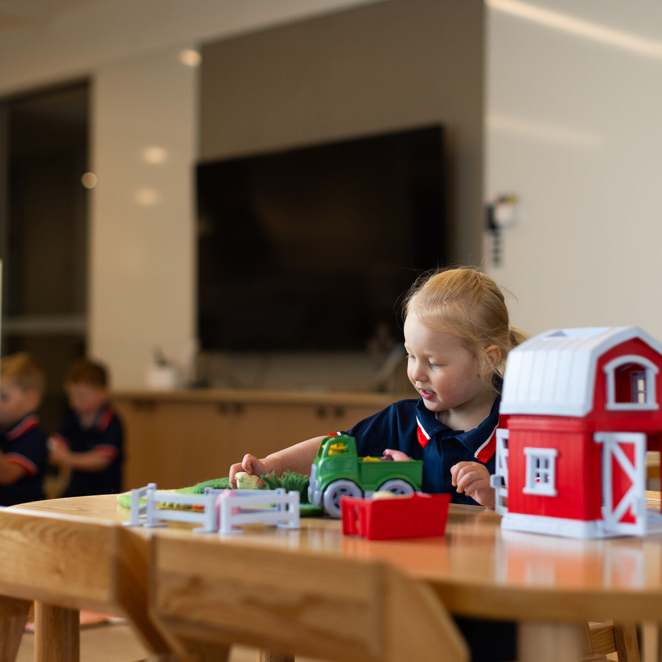 Child engaged in farm-themed imaginative play with a toy barn and tractor at St Michael’s Early Learning Centre.