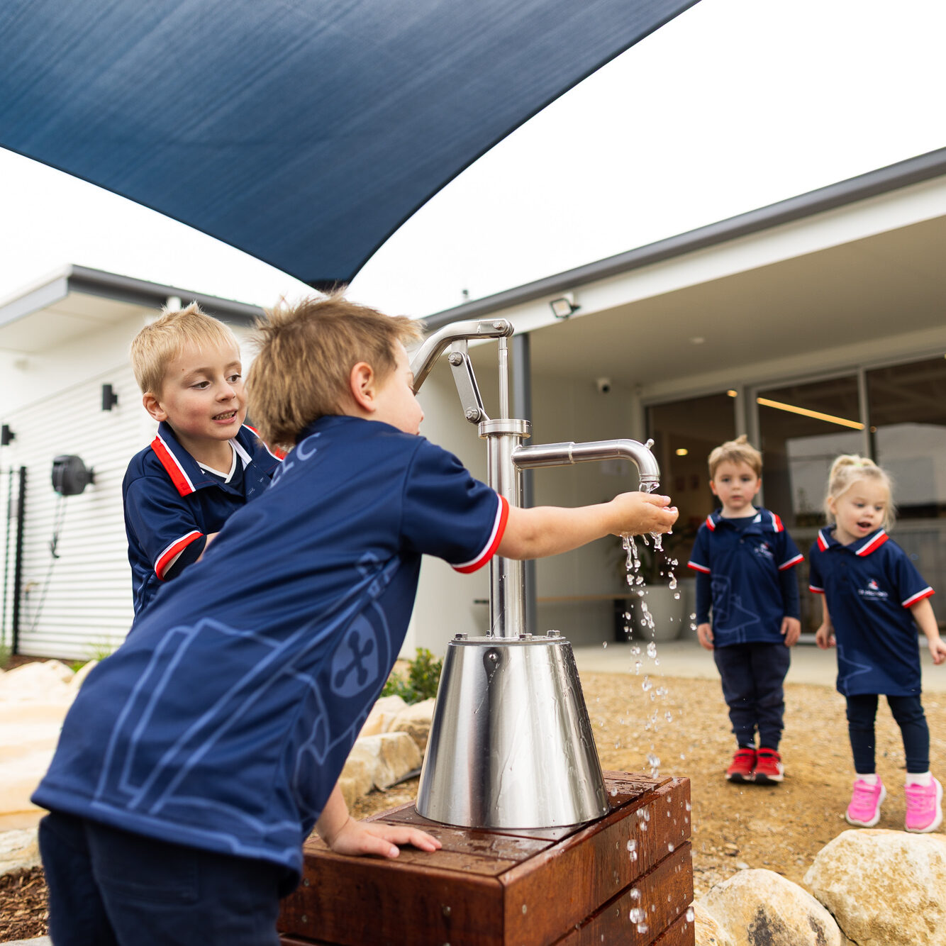 Children exploring a water play station outdoors at St Michael’s Early Learning Centre.